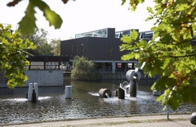 Albertslund Rådhus med rådhussøen og træer i forgrunden.